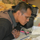 Apprentice Panit Mai watching Yary Livan carve; Cambodian ornaments; 2016: Lowell, Massachusetts